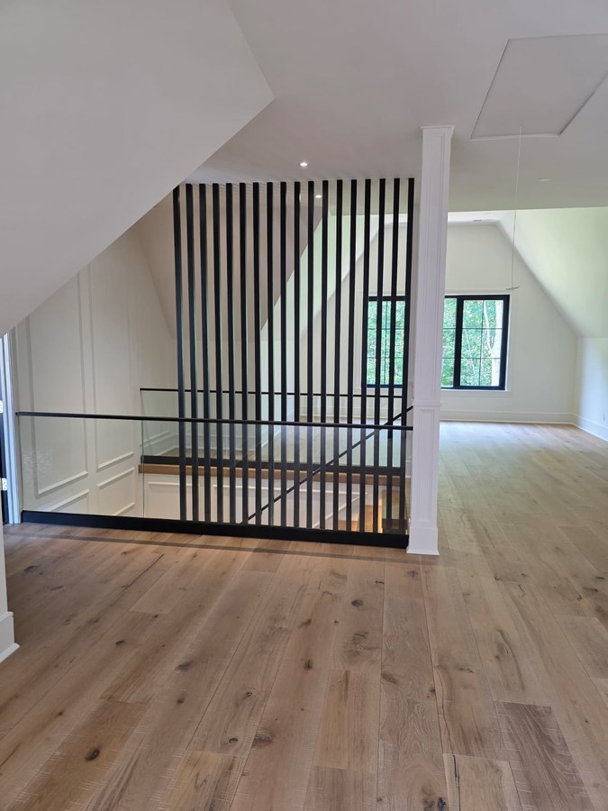 Charleston stair landing with vertical black square tube screen and glass railing