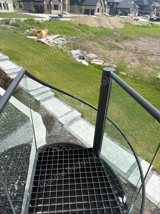 Overhead view of outdoor spiral staircase grating landing with curved glass balustrade in Michigan