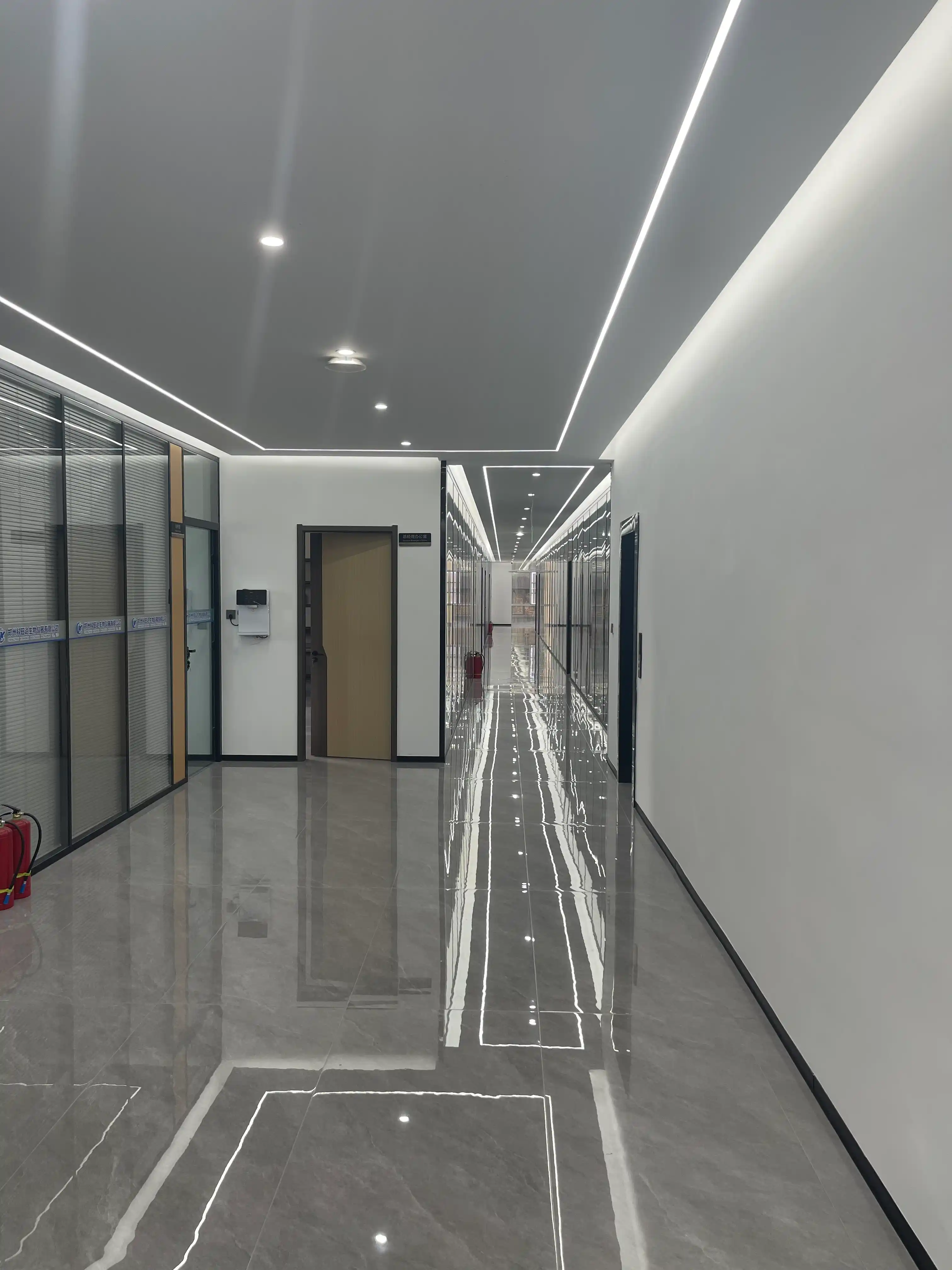 A modern, brightly lit corridor on the second floor of the Geliss factory, housing the R&D center, product testing laboratories, and quality control offices with sleek reflective flooring.